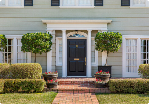 The front door of a beautiful home with light green siding