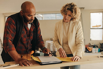 Homeowner stands with a contractor to review details of a home renovation loan.